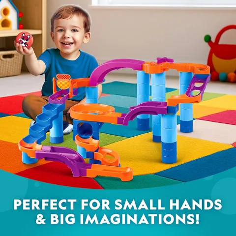 Toddler playing with the ball drop tower on a colorful play mat